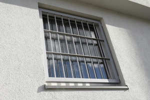 Zdjęcie poglądowe typu zajawka przedstawiające kratę zewnętrzną okna celi PDOZ KPP w Gryficach na zdjęciu widoczną jest również elewacja budynku w kolorze białym.