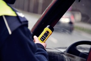 Zjęcie poglądowe przedstawia policjanta prewencji prowadzącego kontrole trzeźwości kierowcy przy pomocy urządzenia alcoblow- zródło : policja.pl
