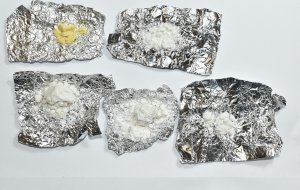 Zdjęcie przedstawia sześć kawałków foli aluminiowej ułożonych w dwóch rzędach, na których znajdują się porcje białego proszku tj. amfetaminy.